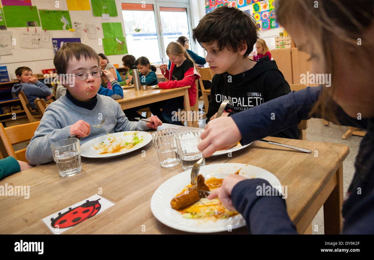 Non-disabled and disabled pupils (in this case a boy suffering from Down's syndrome) have lunch together in their classroom. Stock Photo