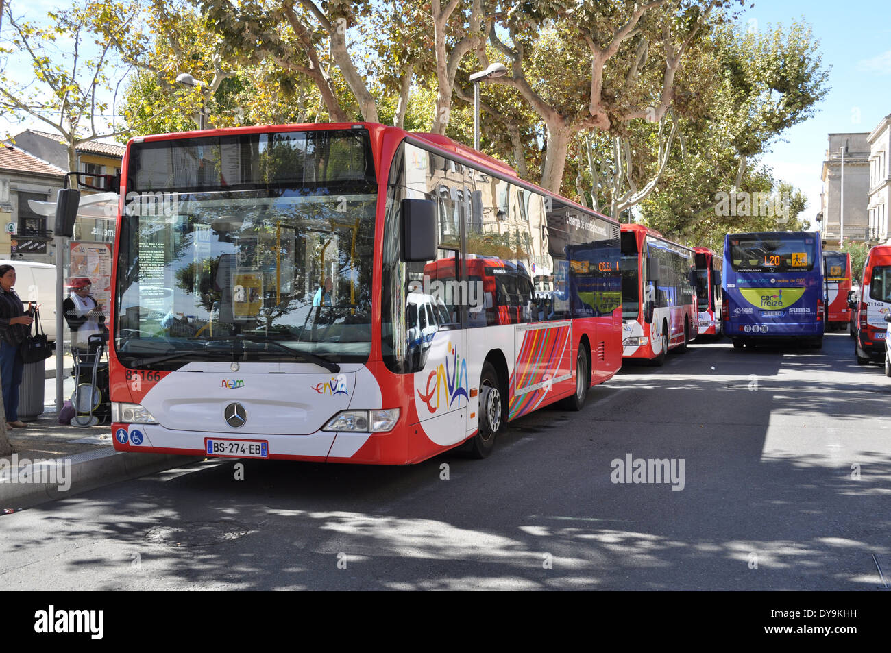 People waiting at bus stop and a line of urban passenger mass transport buses in the centre of town Arles France Stock Photo