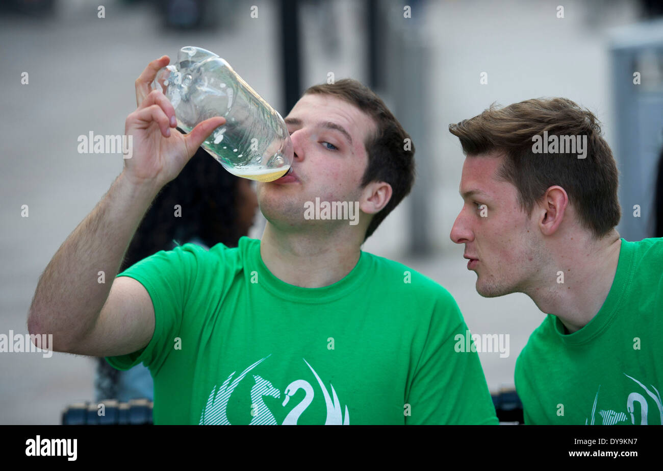 A students drinks a bottle of cider while a friend watches. Stock Photo