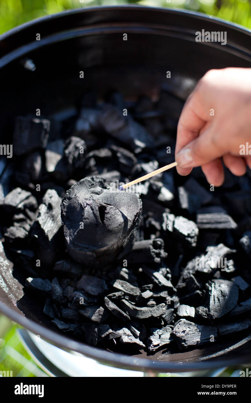 Striking a matchstick, burn up a charcoal in barbecue grill, prepare