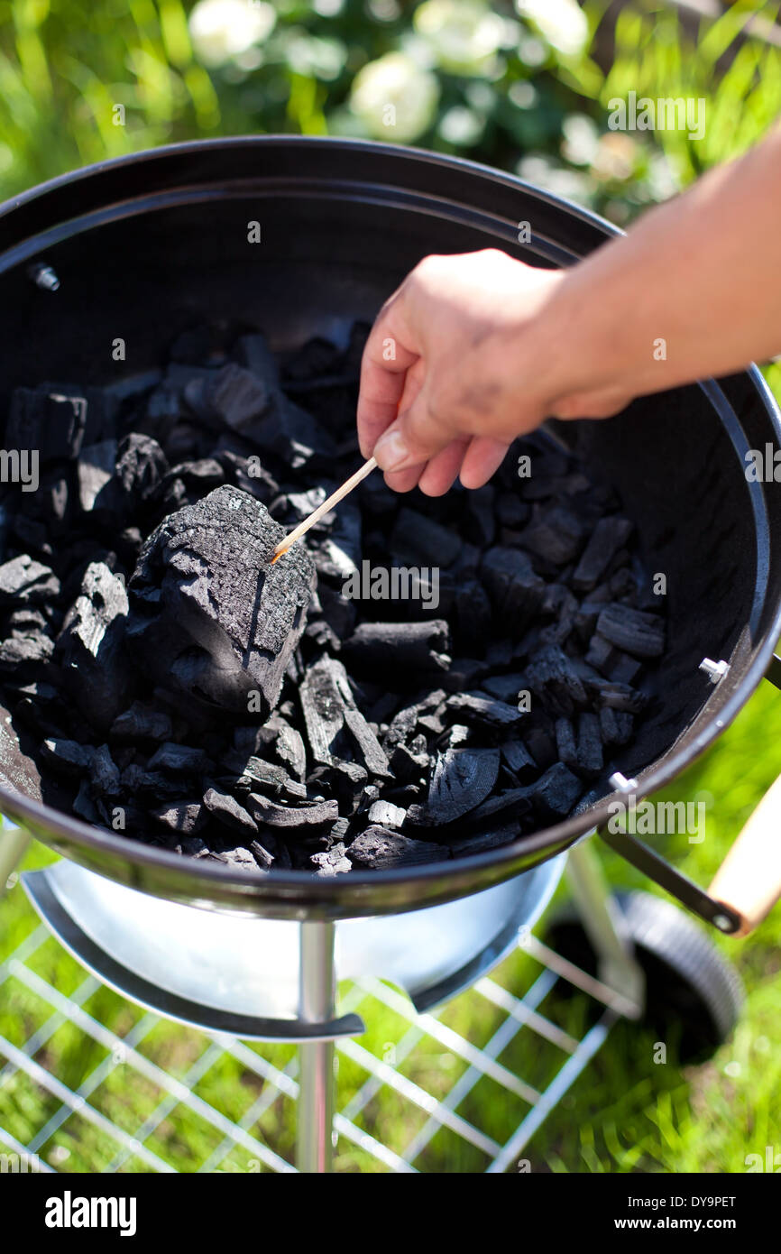 Striking a matchstick, burn up a charcoal in barbecue grill, prepare