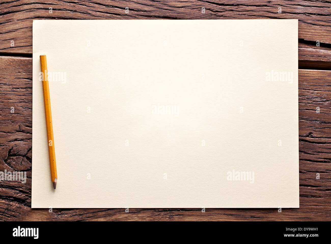 White sheet of paper and pencil on old wooden table. Stock Photo