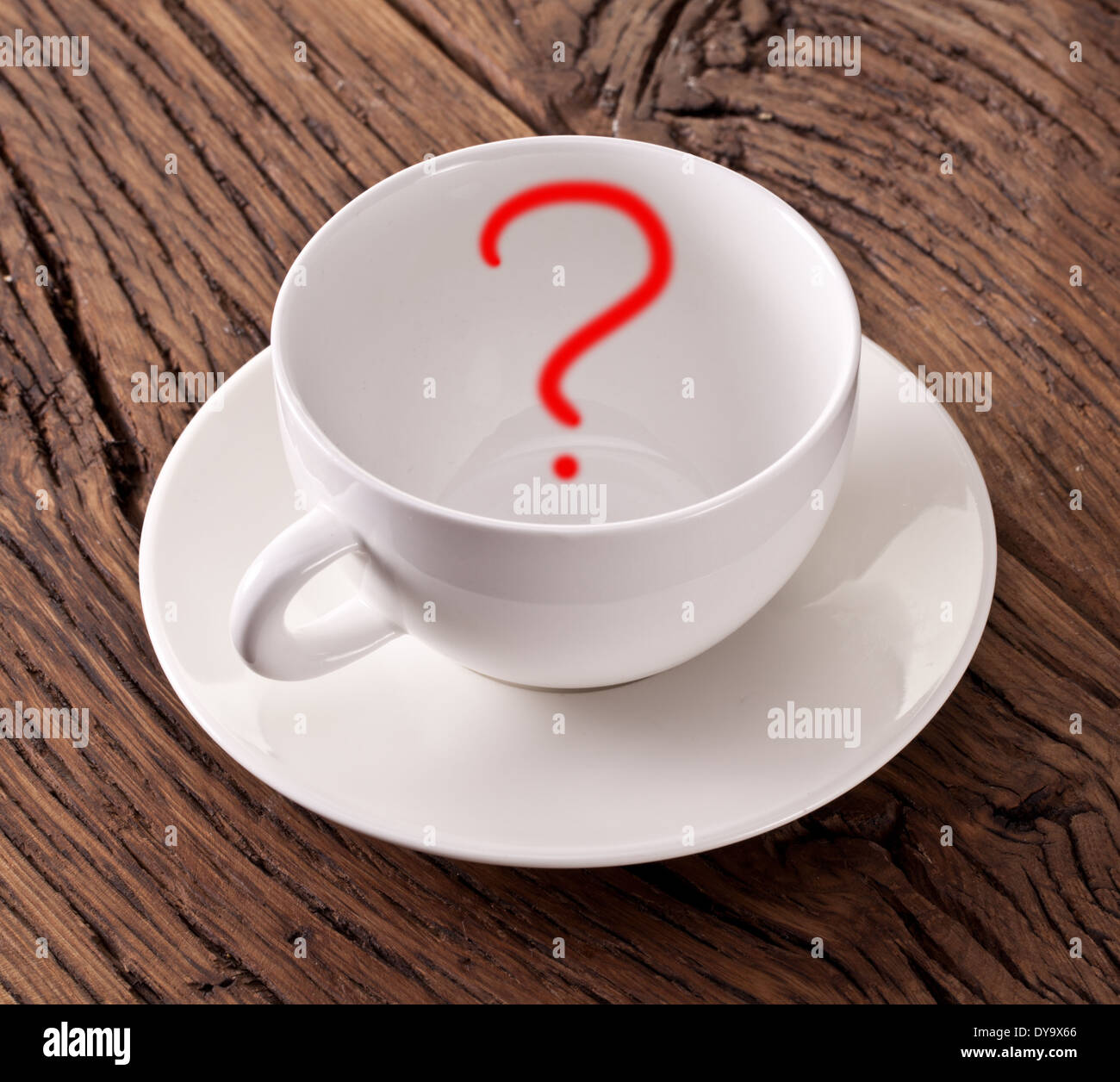 Empty white cup with red question mark in it on old wooden table. Stock Photo