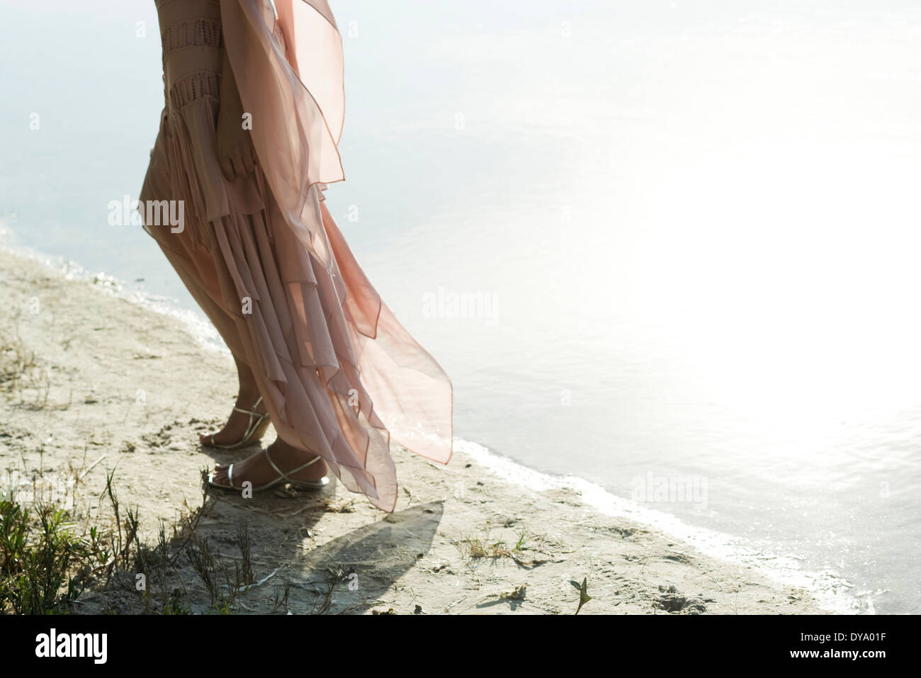 Woman in dress walking along shore, low section Stock Photo - Alamy