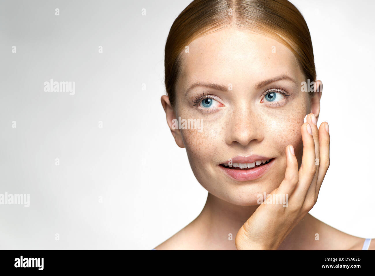 Young woman applying moisturizer to face Stock Photo