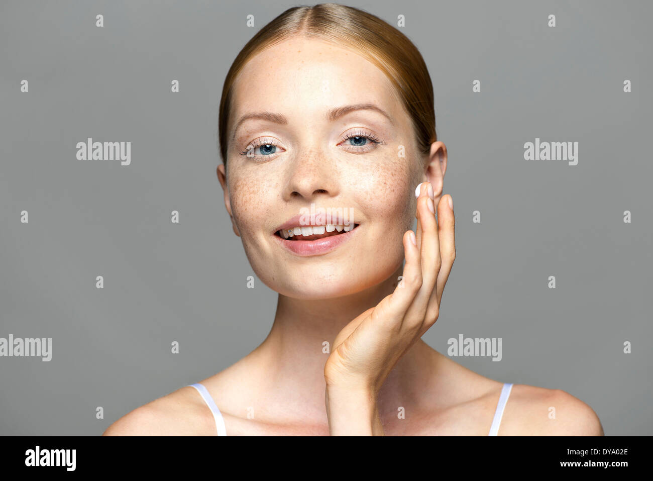 Young woman applying moisturizer to face Stock Photo