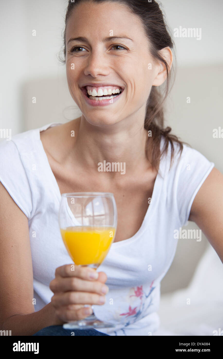Woman holding glass of juice, smiling cheerfully Stock Photo