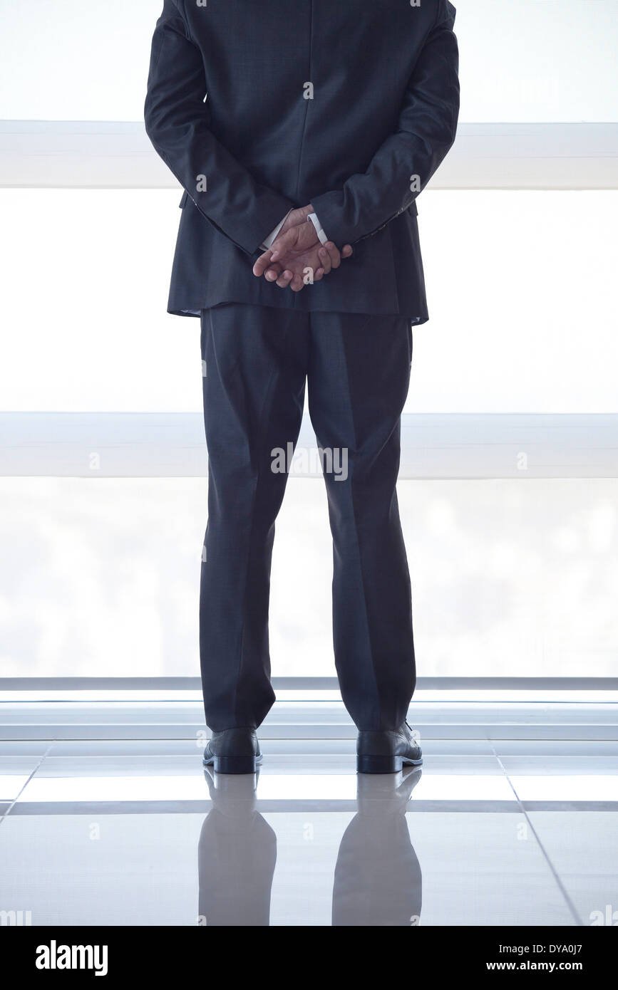 Businessman looking out high rise window at view of city below, rear view Stock Photo