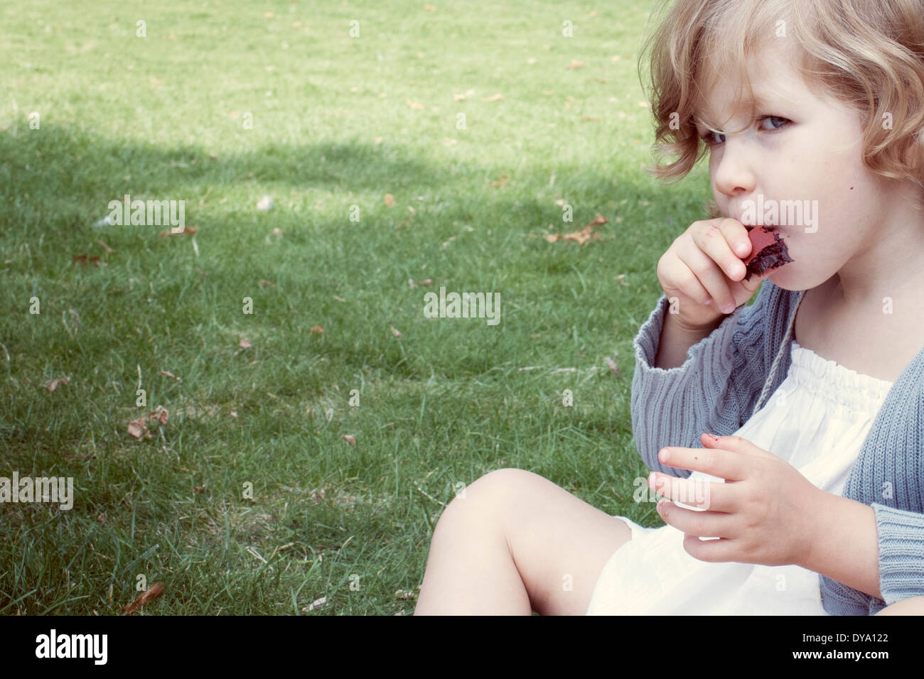 Little girl eating sweet snack outdoors Stock Photo