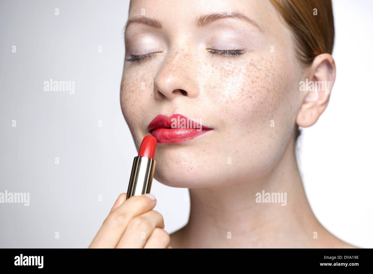 Young woman putting on lipstick Stock Photo