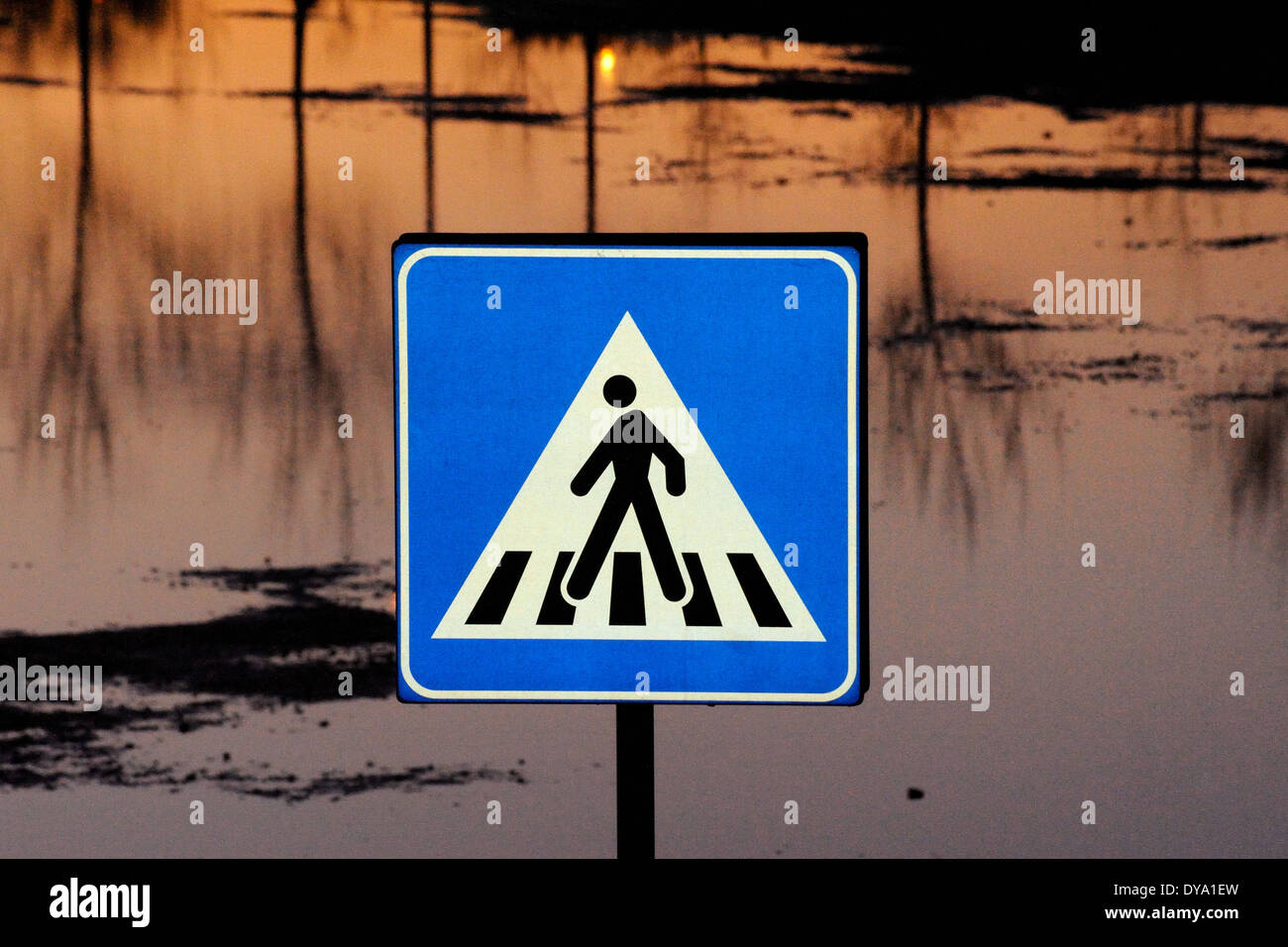 pedestrian crosswalk sign with a man walking on water sunset in background Stock Photo