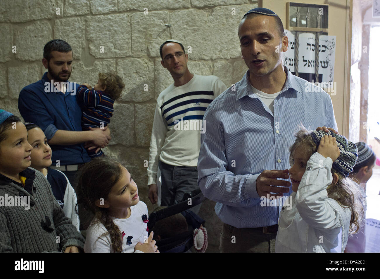 A family performs a Halaqah (Sephardic Jews) or Upsherin (Ashkenazi Jews) ceremony at the tomb of the Prophet Samuel, cutting their three-year-old son's hair for the first time. This is the traditional burial site of the biblical Prophet Samuel, just north of Jerusalem. The tomb is located in an underground chamber inside a small synagogue in the 18th century Nabi Samwil Mosque, built on the remains of a Crusader-era fortress. Stock Photo