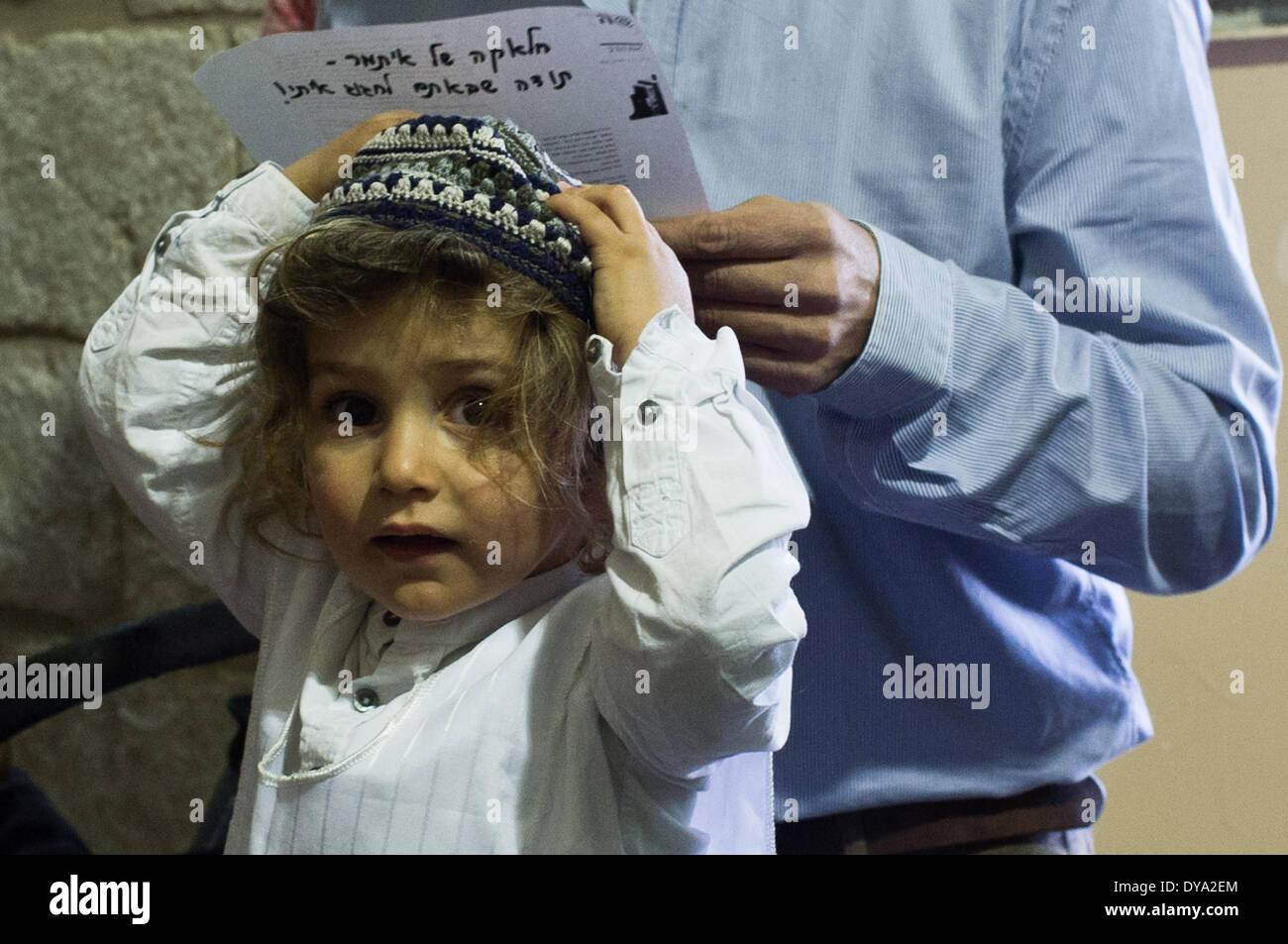 A family performs a Halaqah (Sephardic Jews) or Upsherin (Ashkenazi Jews) ceremony at the tomb of the Prophet Samuel, cutting their three-year-old son's hair for the first time. This is the traditional burial site of the biblical Prophet Samuel, just north of Jerusalem. The tomb is located in an underground chamber inside a small synagogue in the 18th century Nabi Samwil Mosque, built on the remains of a Crusader-era fortress. Stock Photo