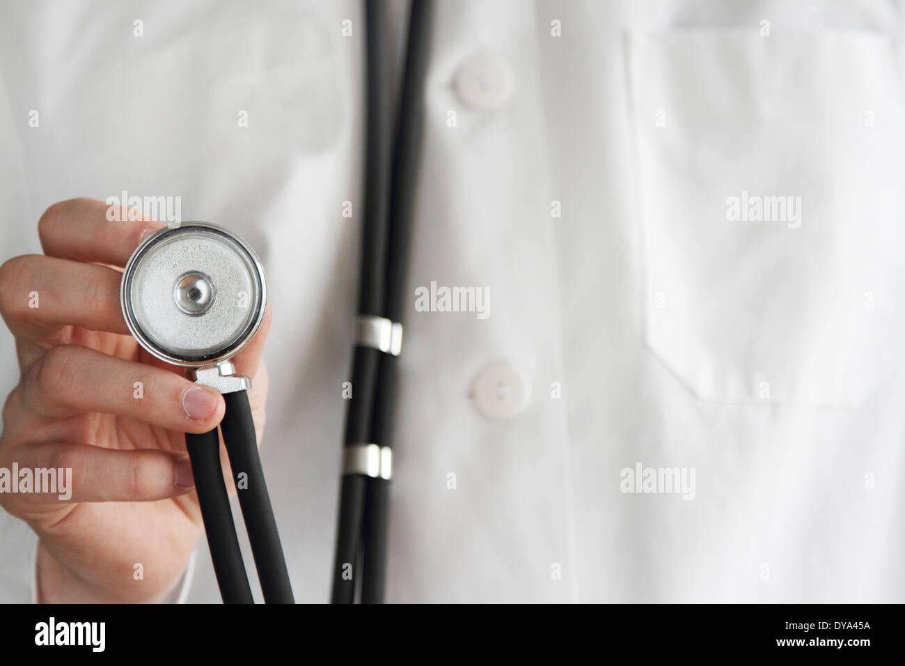 young doctor with white coat and stethoscope in one hand Stock Photo