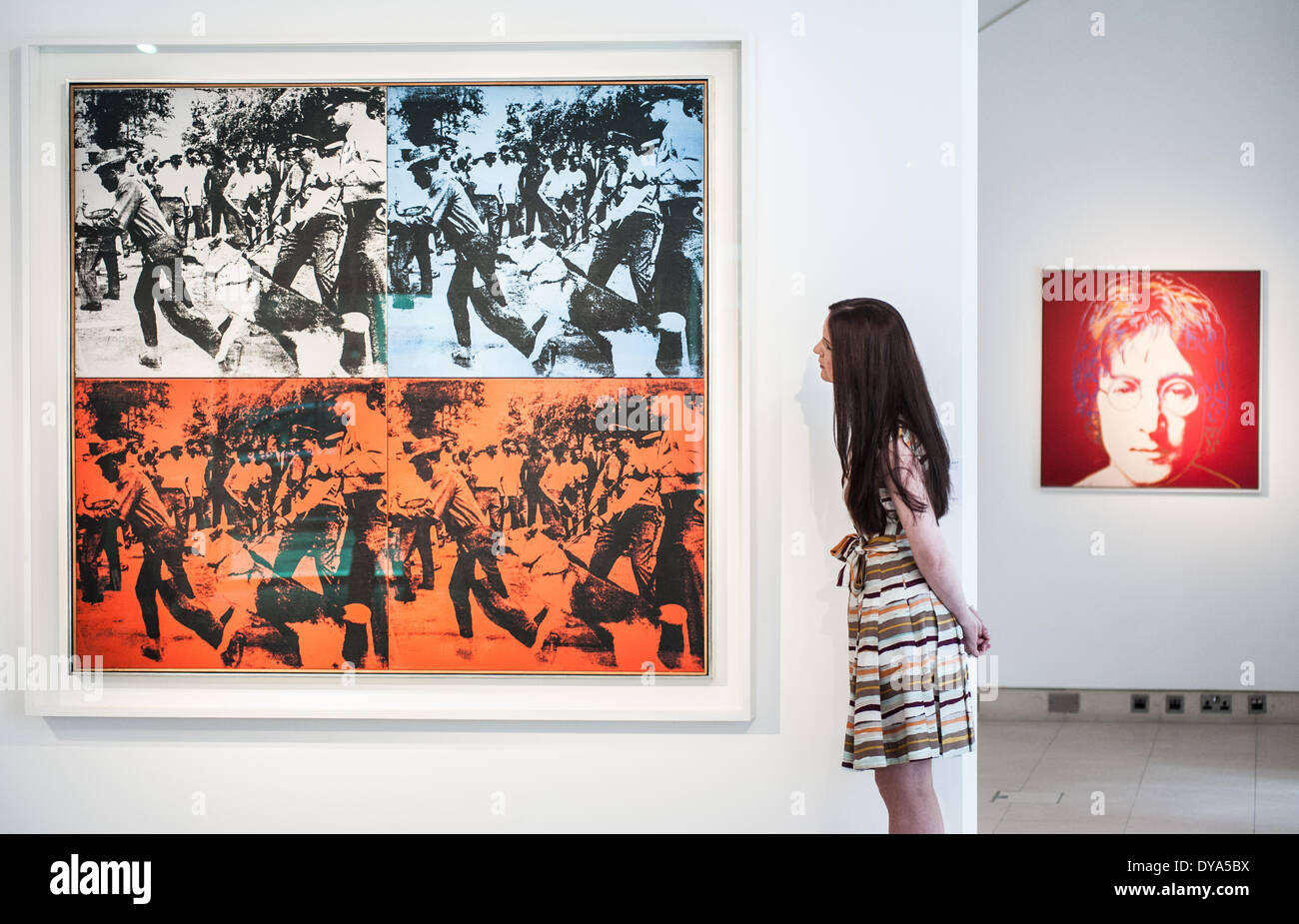London, UK - 11 April 2014: a Christie’s employee looks at 'Race Riot' by Andy Warhol during the preview of the Post-War and Contemporary Art evening sale that will take place in New York on the 13th May. Credit:  Piero Cruciatti/Alamy Live News Stock Photo