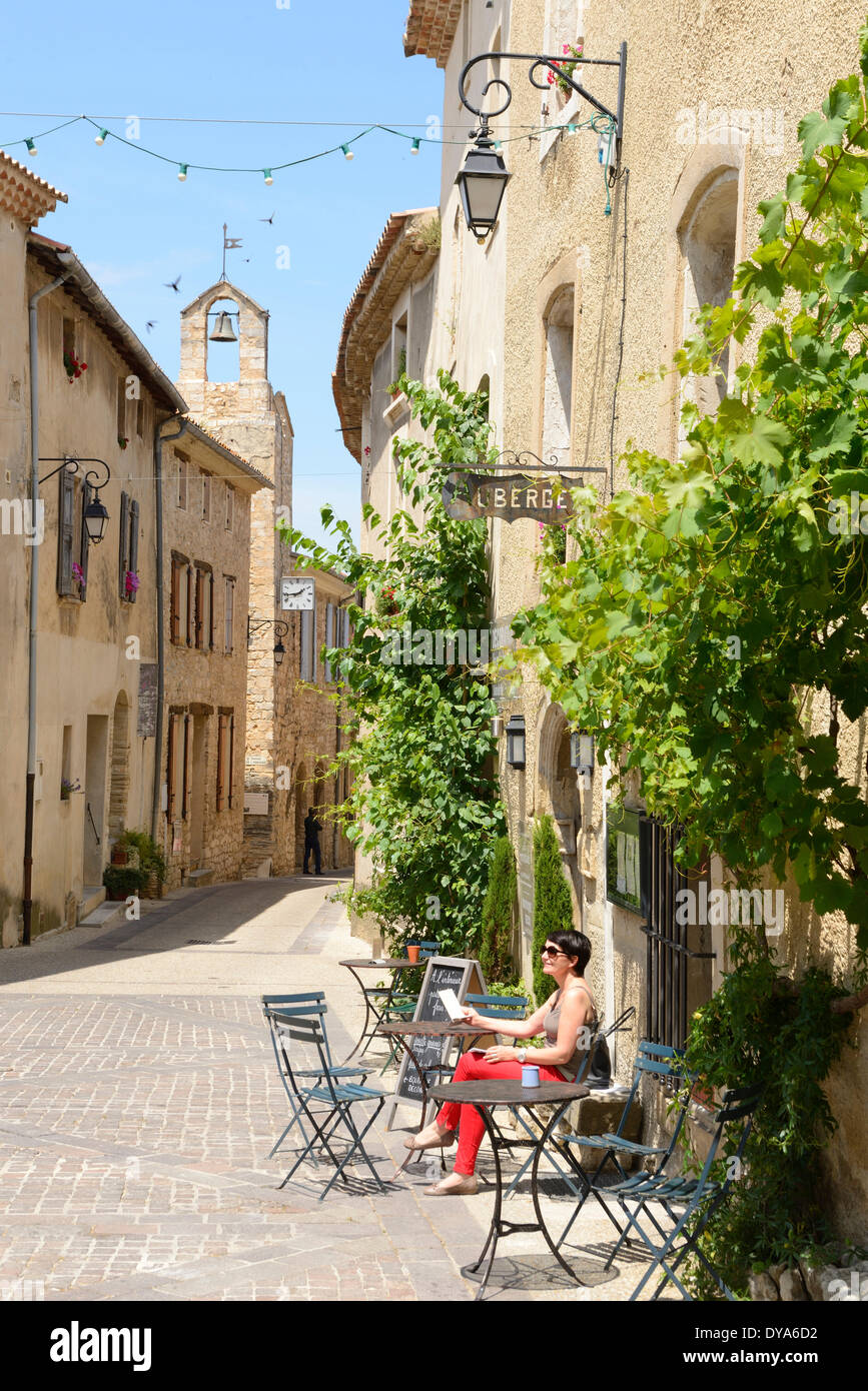 Europe France Provence Vaucluse Venasque street village stone buildings street town woman french red pants sit cafe Stock Photo