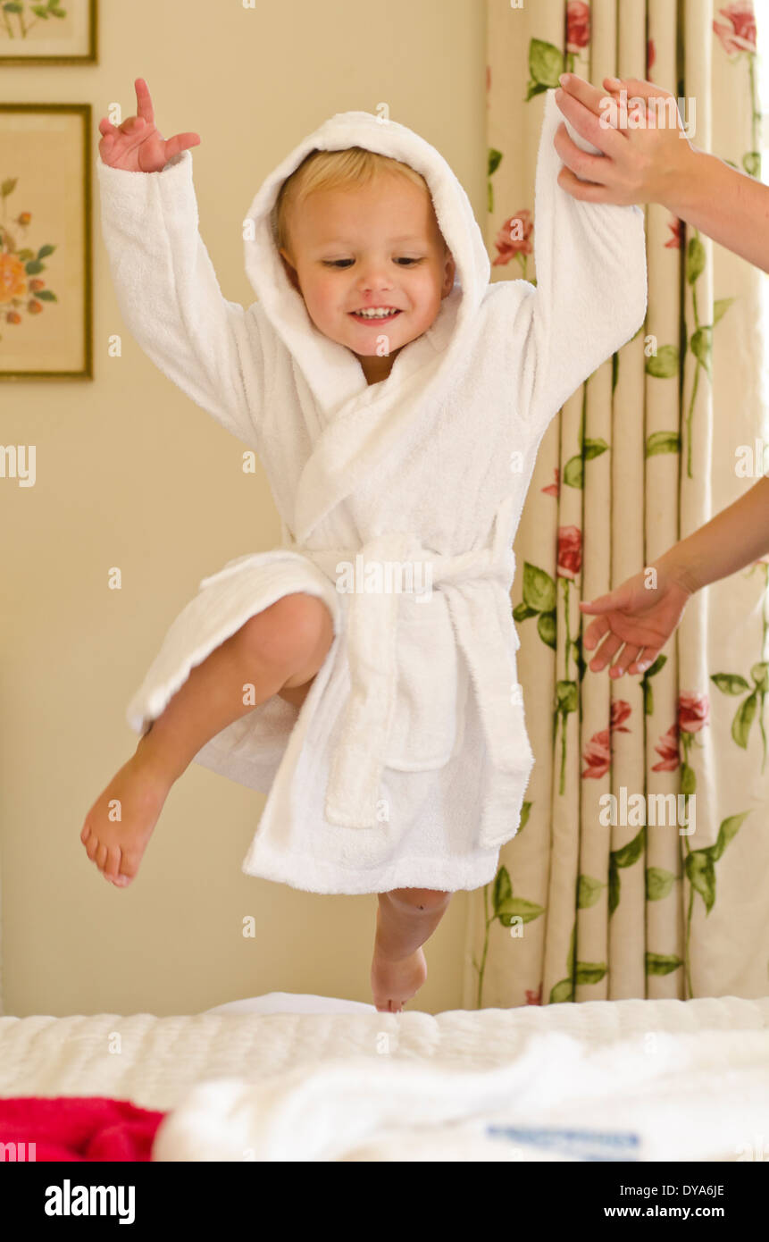 Toddler boy jumping on bed in bathrobe Stock Photo Alamy