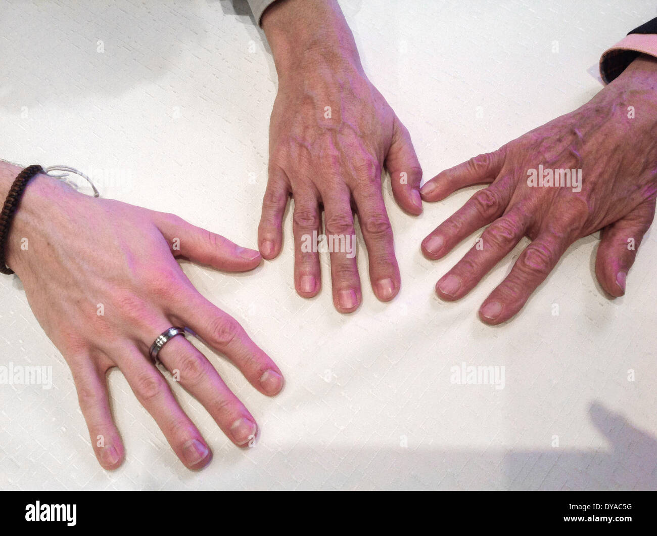 The hands of grandfather, son and grandson on a table. April 2014 Stock Photo