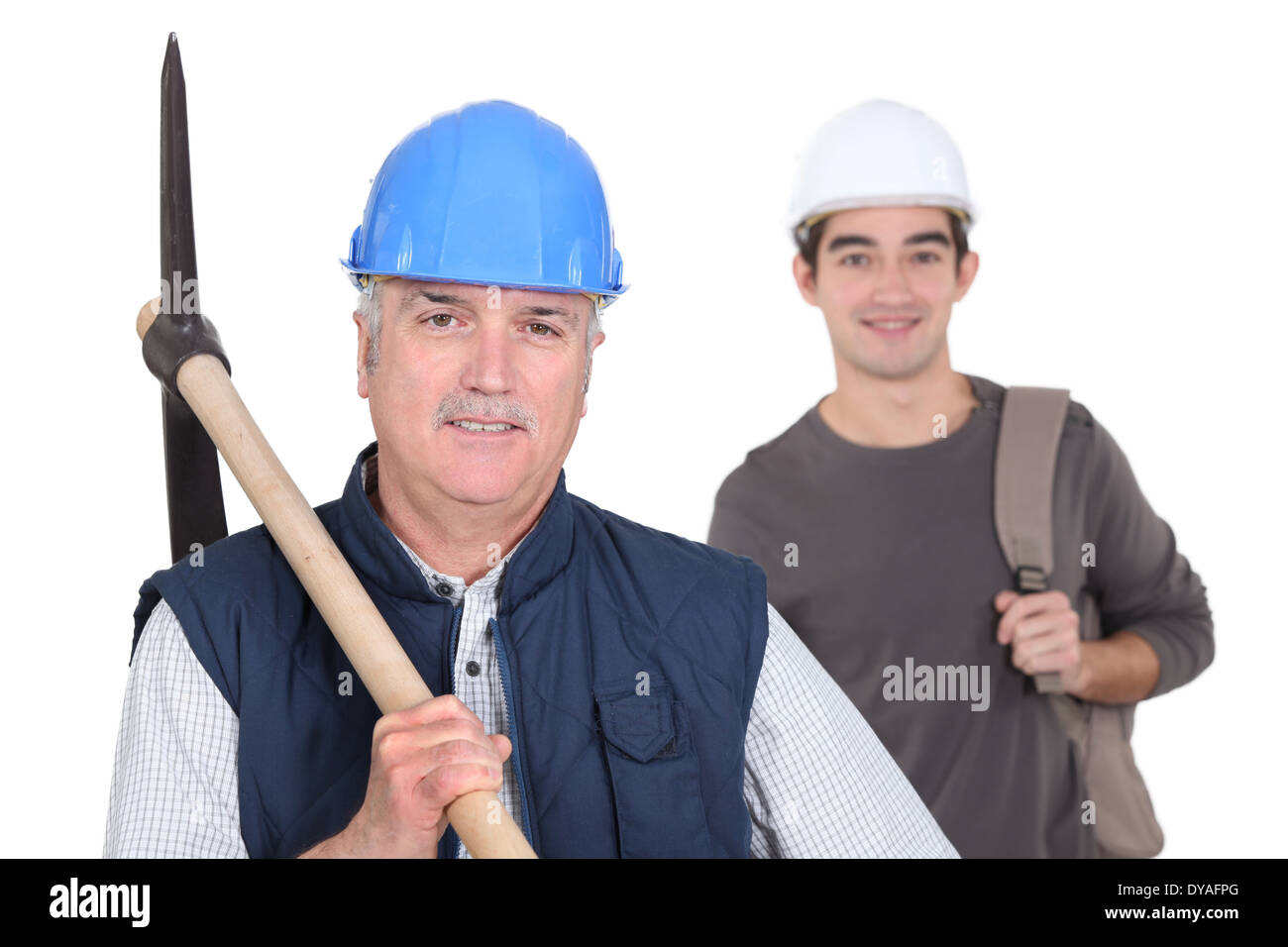 mature manual worker and young apprentice in background Stock Photo