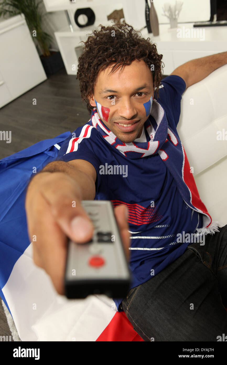 French football supporter holding television remote control Stock Photo