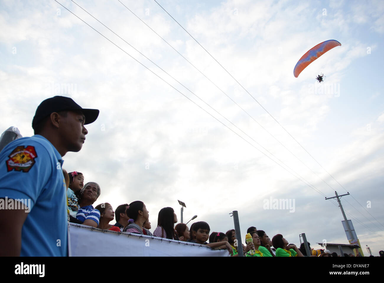 Lubao, Pampanga, Philippines. 11th Apr, 2014. People watch a paramotor pass by at the Philippine International Hot Air Balloon Festival on April 11, 2014. The Philippine International Hot Air Ballon Festival featured 21 countries with 37 balloons. Credit:  Mark Cristino/NurPhoto/ZUMAPRESS.com/Alamy Live News Stock Photo