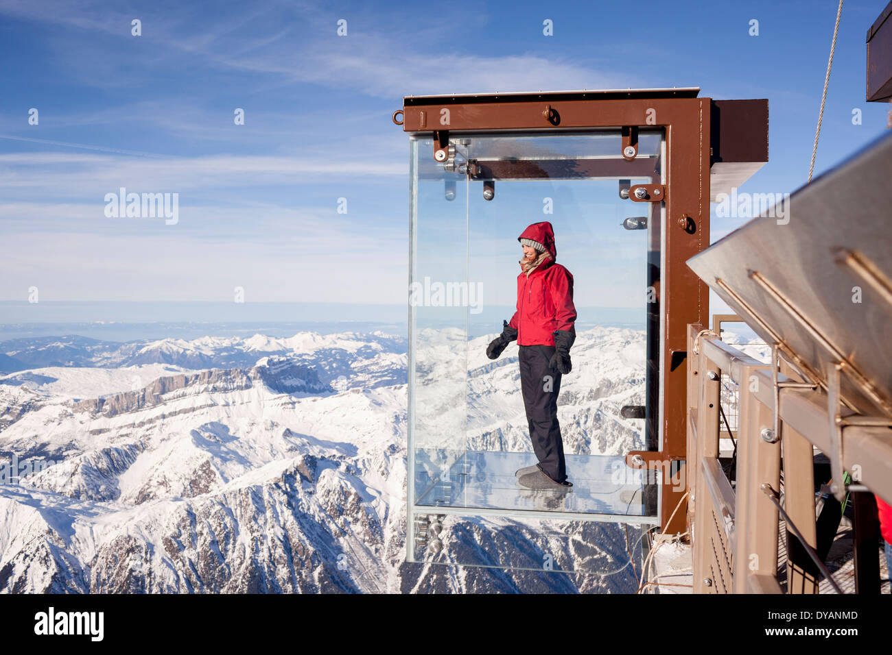 A tourist stands in the 'Step into the Void' glass box on the Aiguille Du Midi (3842m) mountain top above Chamonix Mont-Blanc Stock Photo