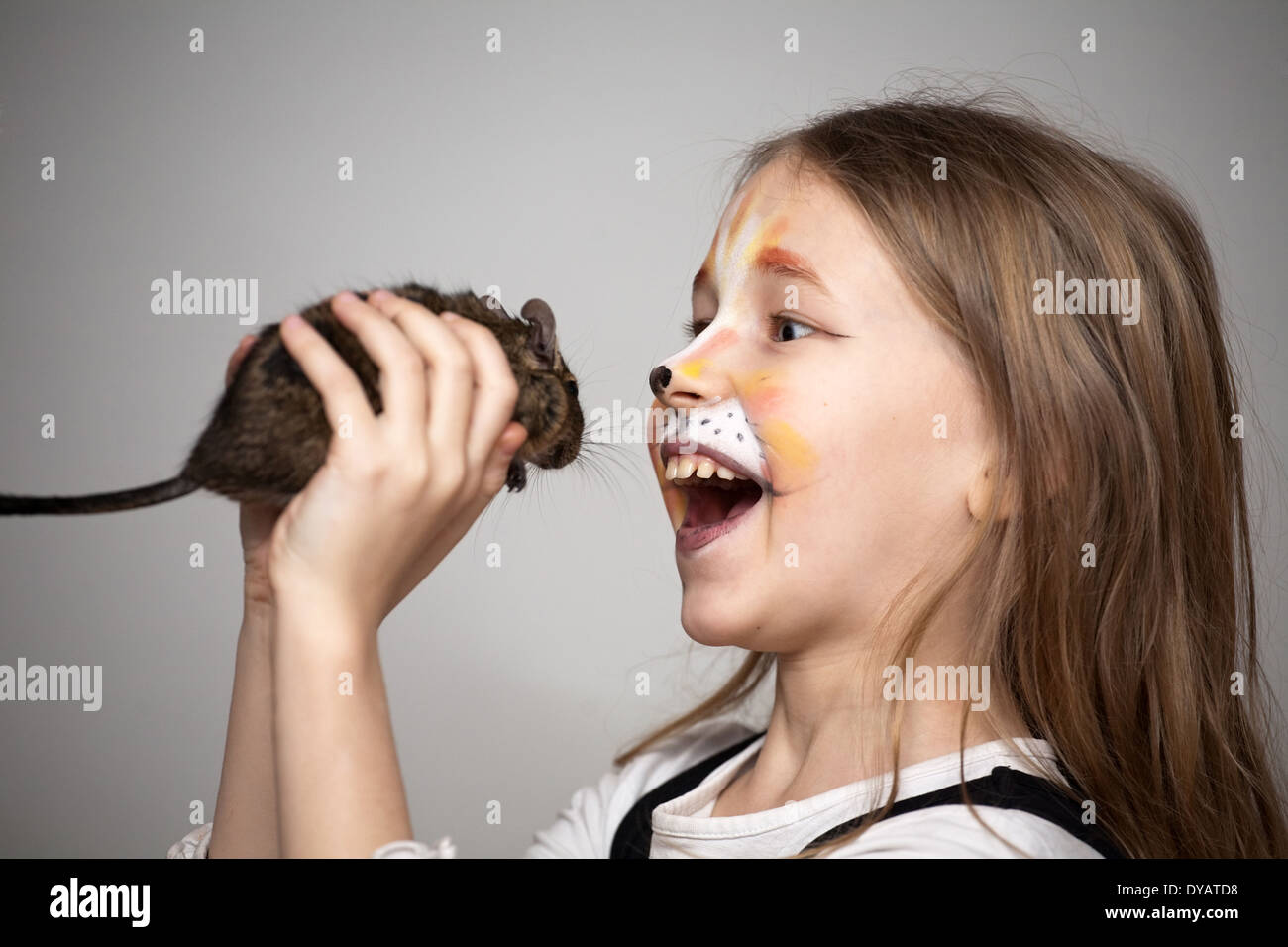 little girl with cat painting makeup on the face catching the mouse Stock Photo