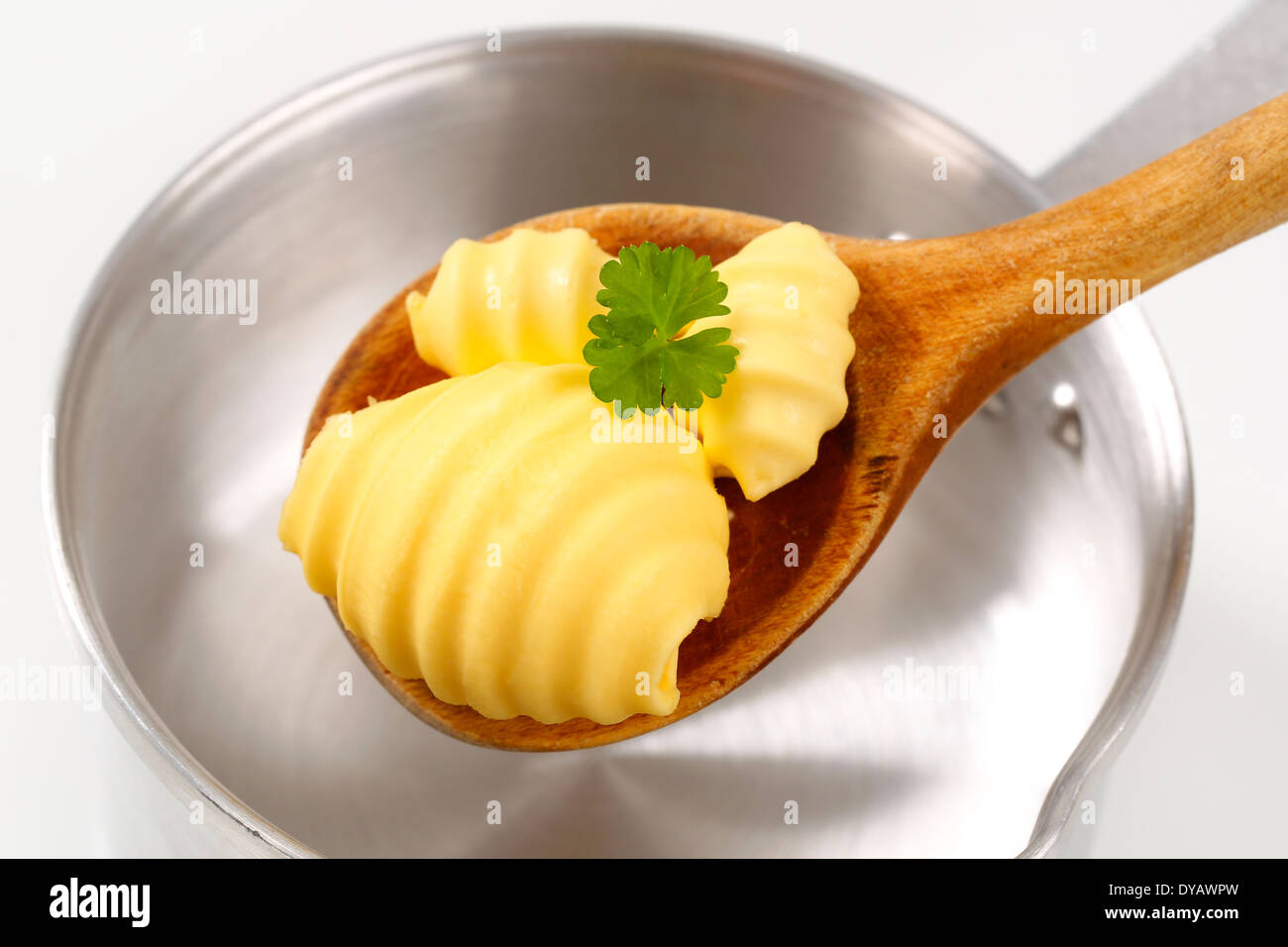 Butter curls on wooden spoon and saucepan Stock Photo
