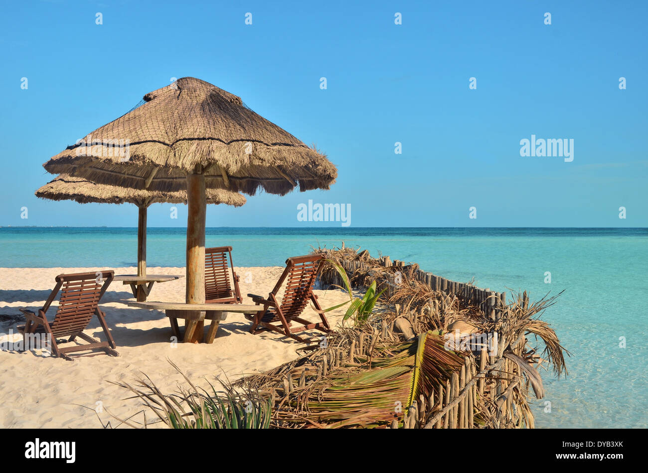 Chairs and umbrella on a beach with shadow from palm tree Stock Photo