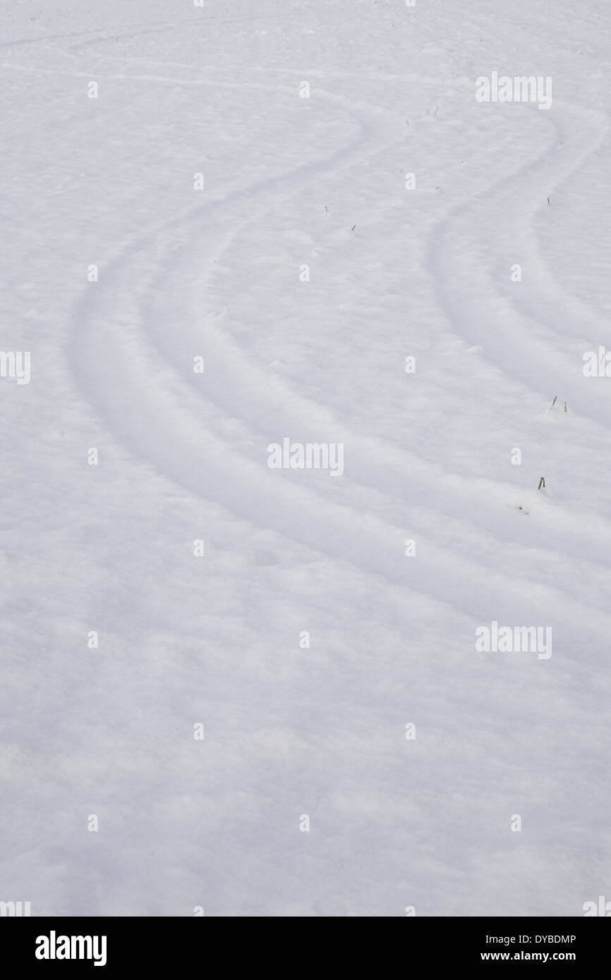 winter snow scene in The south of England showing wavy tyre tracks in a deep snowy field Stock Photo