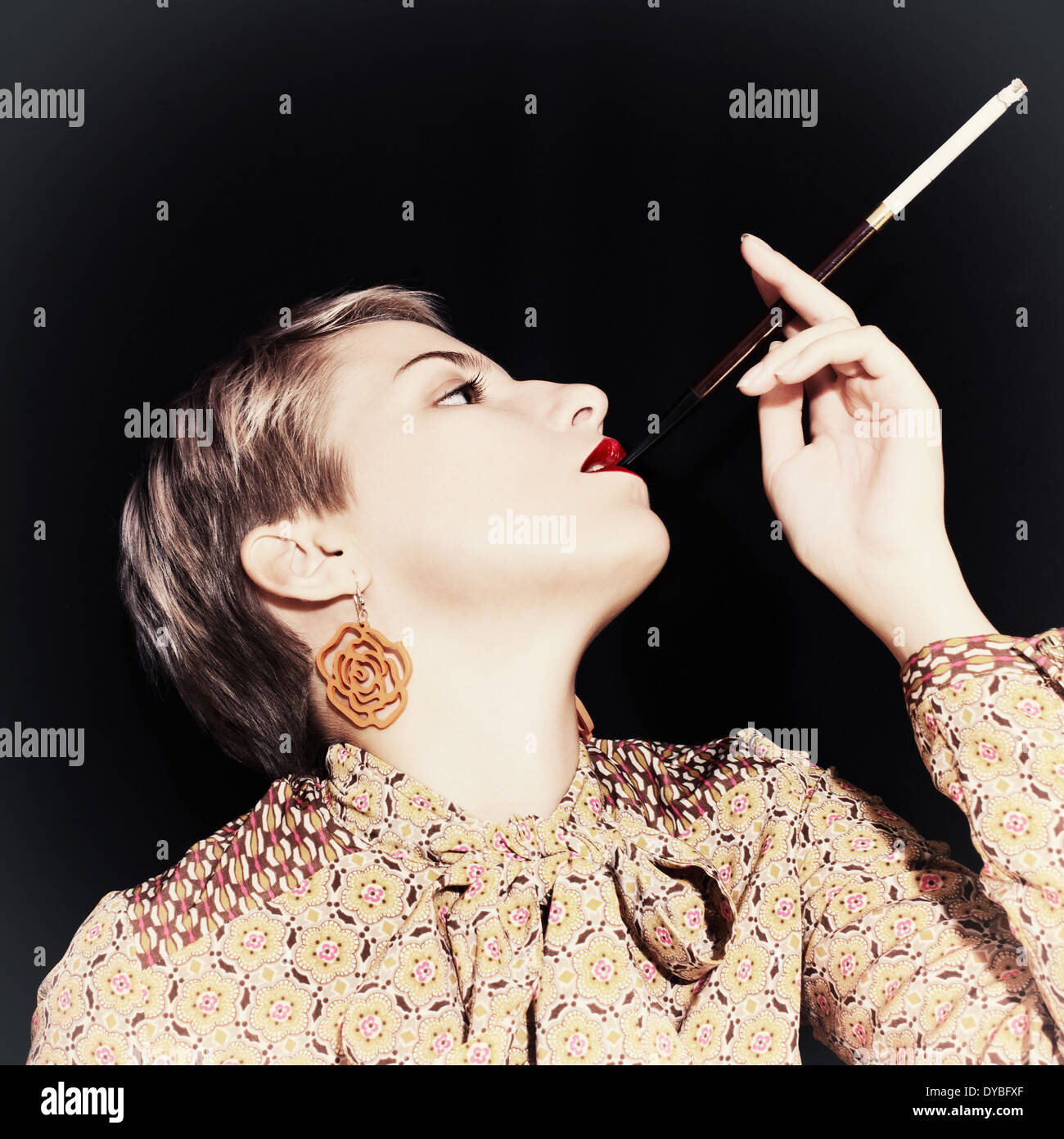 Retro portrait of young woman with cigarette on black background Stock Photo