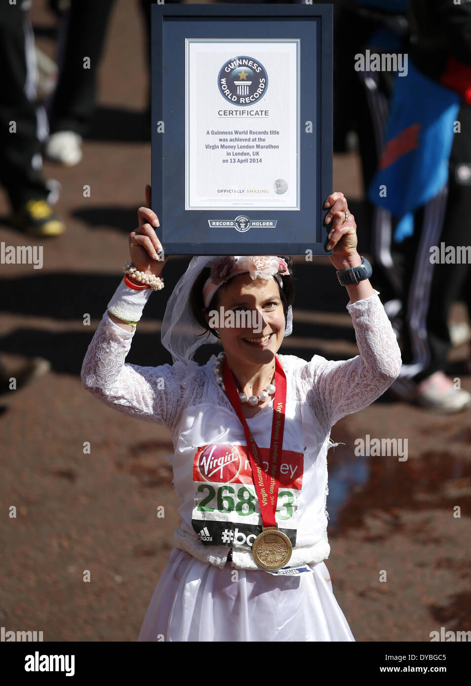 London, Charity and Ballot of 2014 London Marathon in London. 13th Apr, 2014. British Sarah Dudgeon wearing a wedding dress poses with the Guinness Certificate after crossing the finish line during Group Club, Charity and Ballot of 2014 London Marathon in London, Britain on Apr. 13, 2014. Sarah Dudgeon finished the run with 3 hours 16 minutes and 44 seconds to be the fastest runner to finish the London Marathon in a wedding dress. Credit:  Xinhua /Wang Lili/Xinhua/Alamy Live News Stock Photo