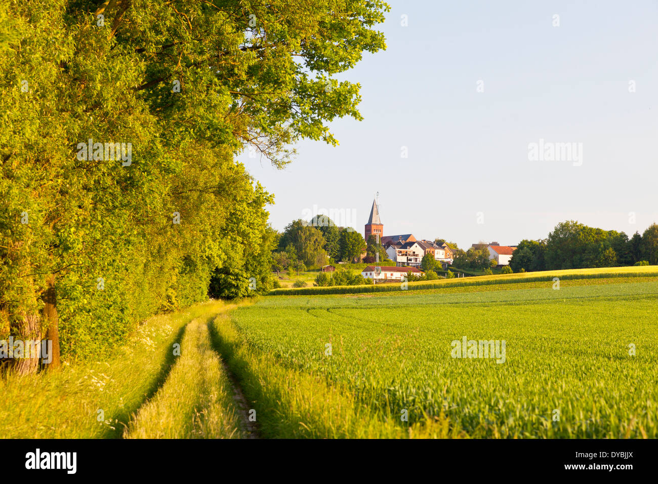 Dirt road and field with a village in the background. Stock Photo