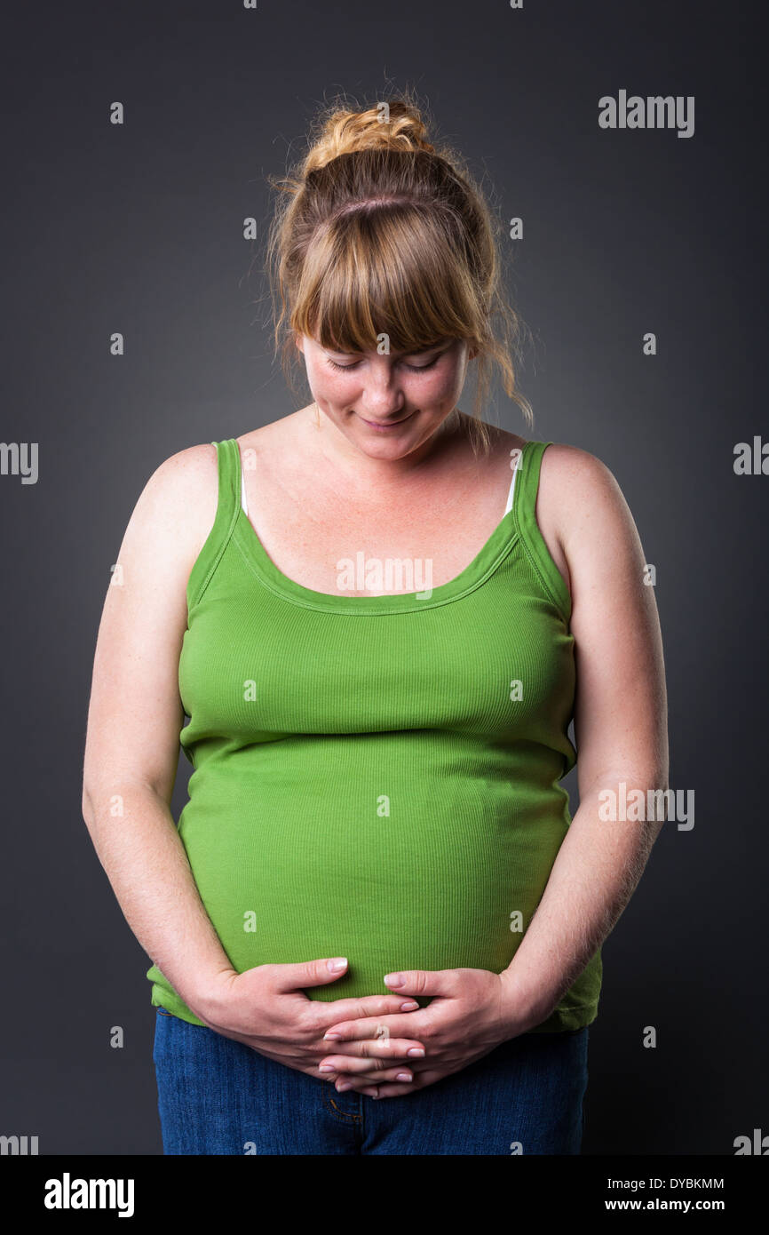 Happy young prengant woman in studio - dark background Stock Photo