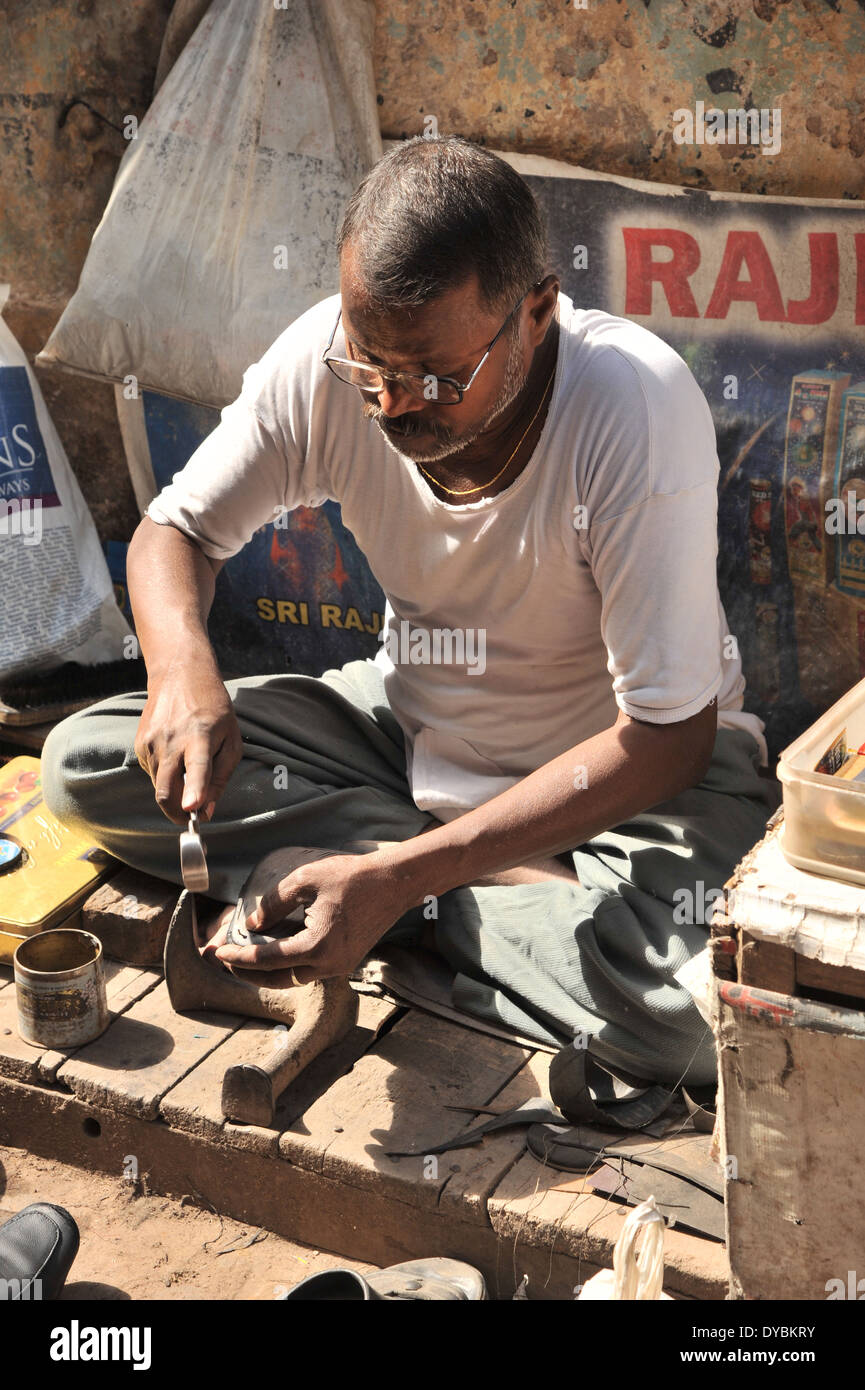 Delhi, India. April 6th 2014. A cobbler repairs shoes on the streets of Old Delhi. India Stock