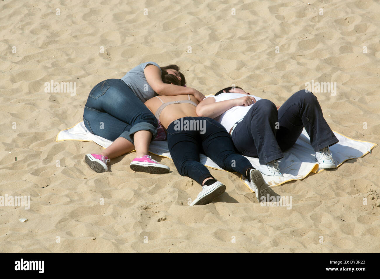 three girls friends cuddling on beach sleeping embrace Stock Photo