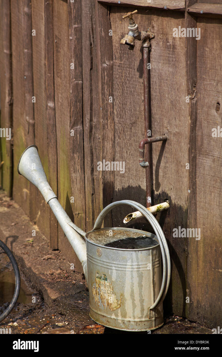 full watering can and tap Stock Photo Alamy