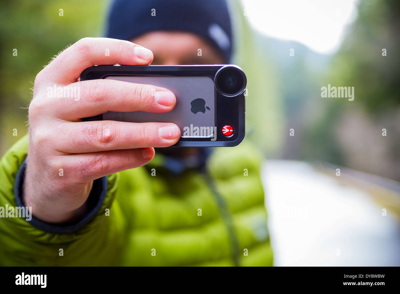 Oakridge, Oregon, USA - February 19,2014: Photographer using an iPhone 5S with Manfrotto lens attached outdoors. Stock Photo