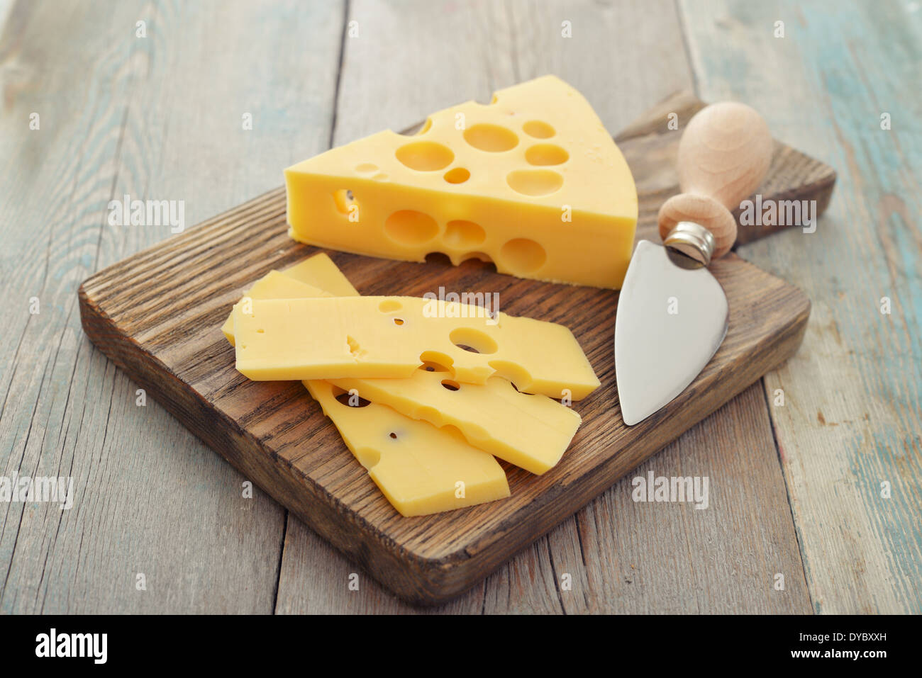 Cheese with big holes and knife on wooden cutting board Stock Photo Alamy