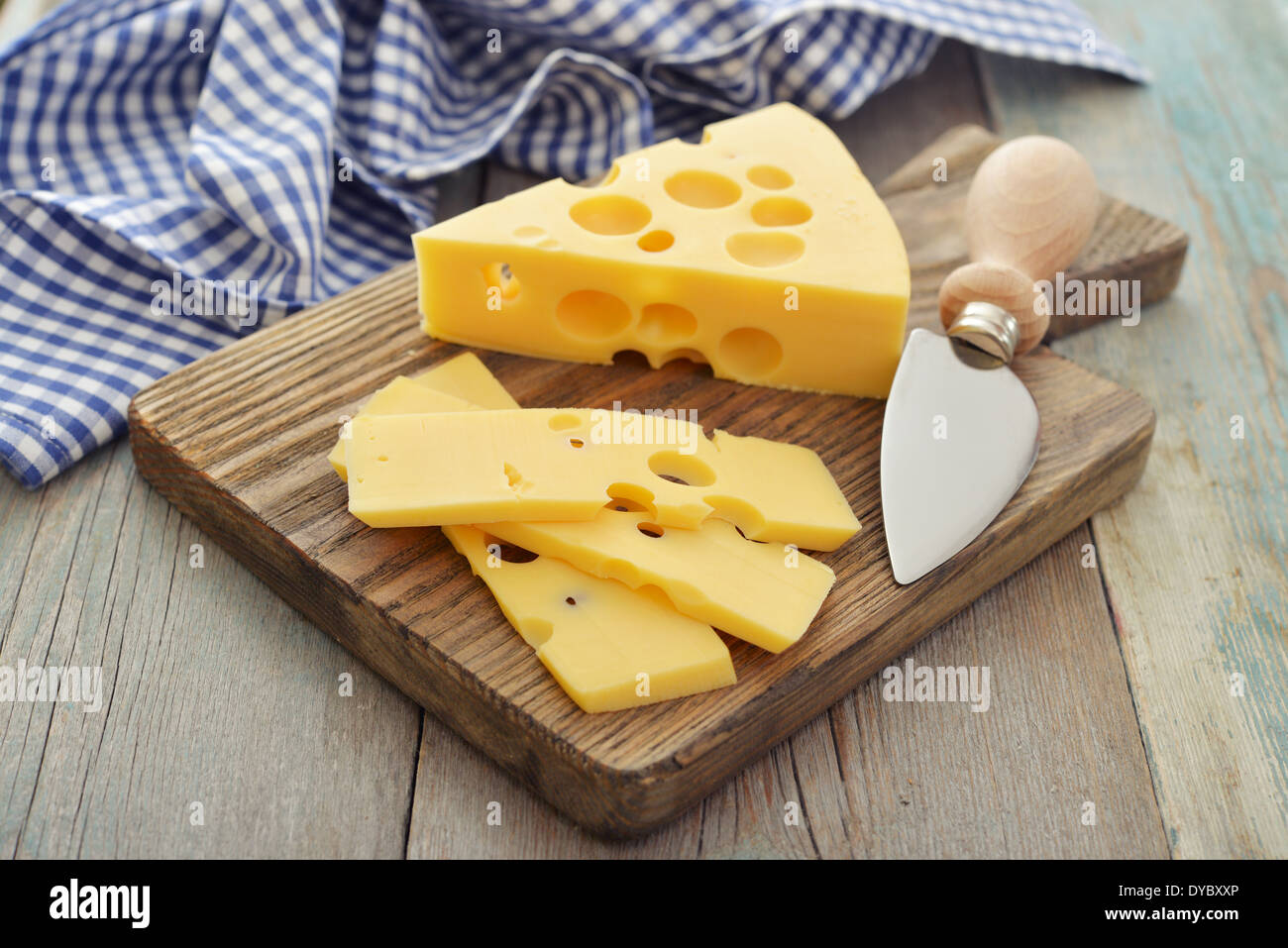 Cheese with big holes and knife on wooden cutting board Stock Photo Alamy