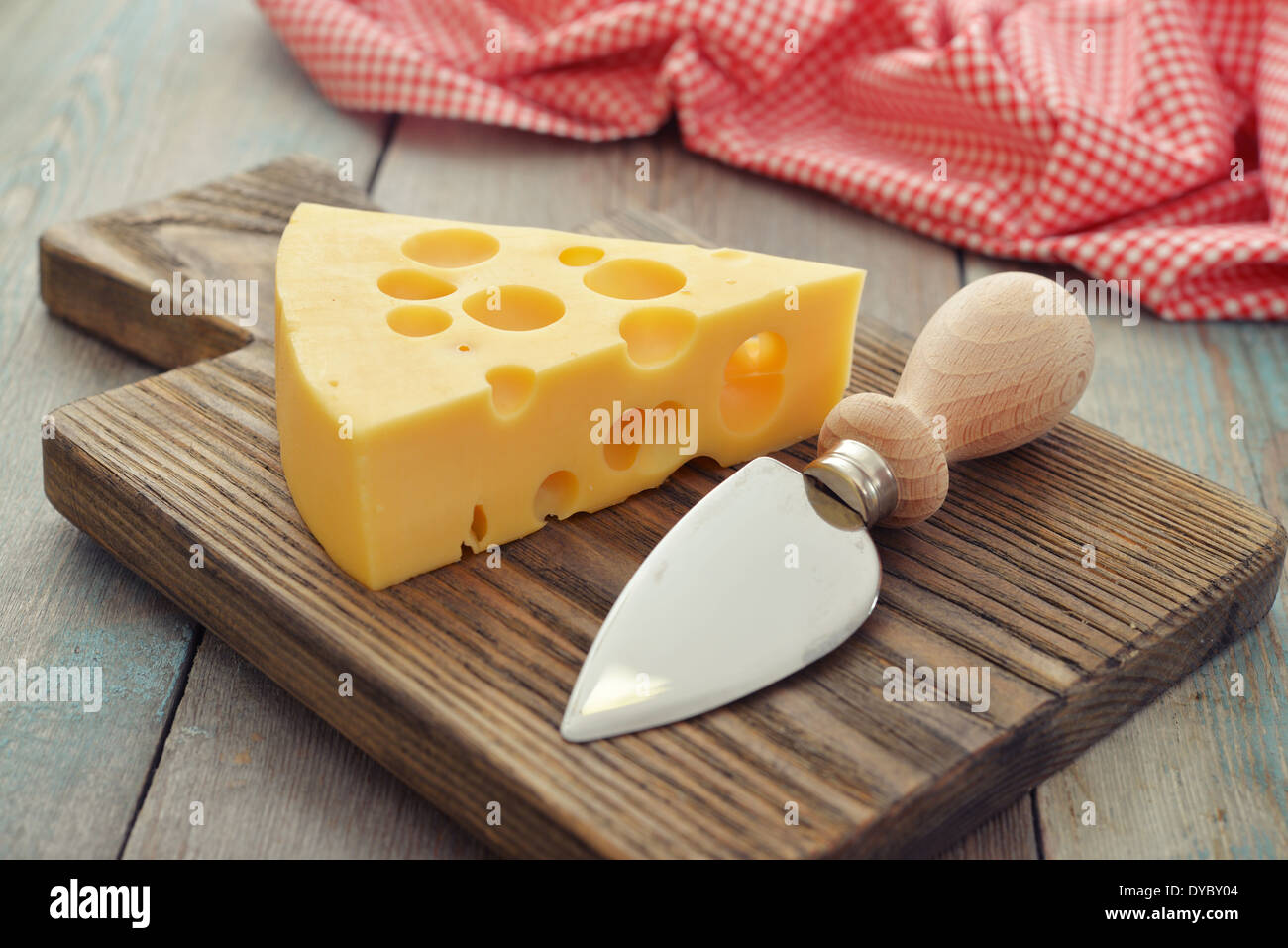 Cheese with big holes and knife on wooden cutting board Stock Photo Alamy