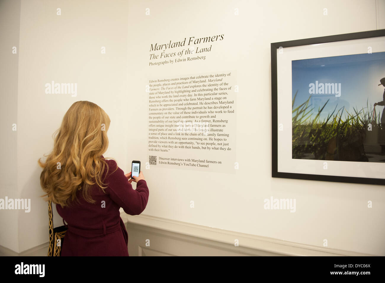 Woman taking a picture of a QR code at a fine art exhibit Stock Photo