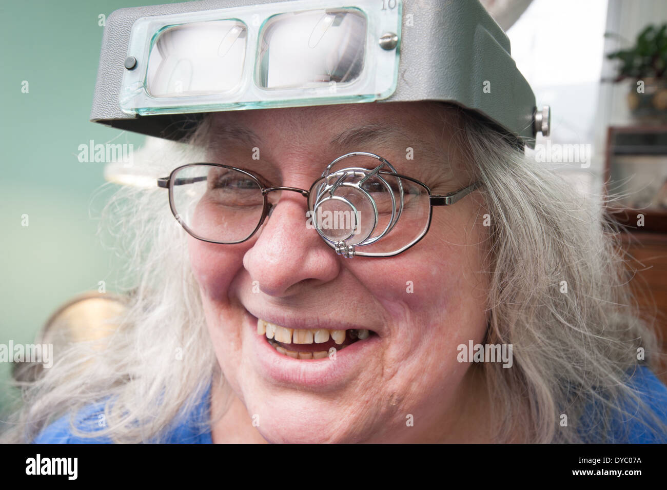 Woman working on a silver engraving and using an old fashioned loupe Stock Photo
