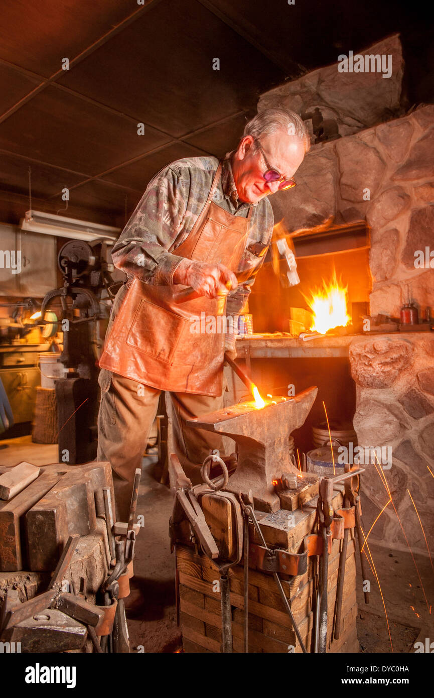 Bladesmith using coal stove to weld and hammer metal Stock Photo