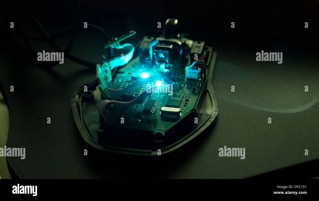 Computer PC mouse dismantled taken apart inside circuit mouse wheel board cables wires mouse mat wooden table led light glowing Stock Photo