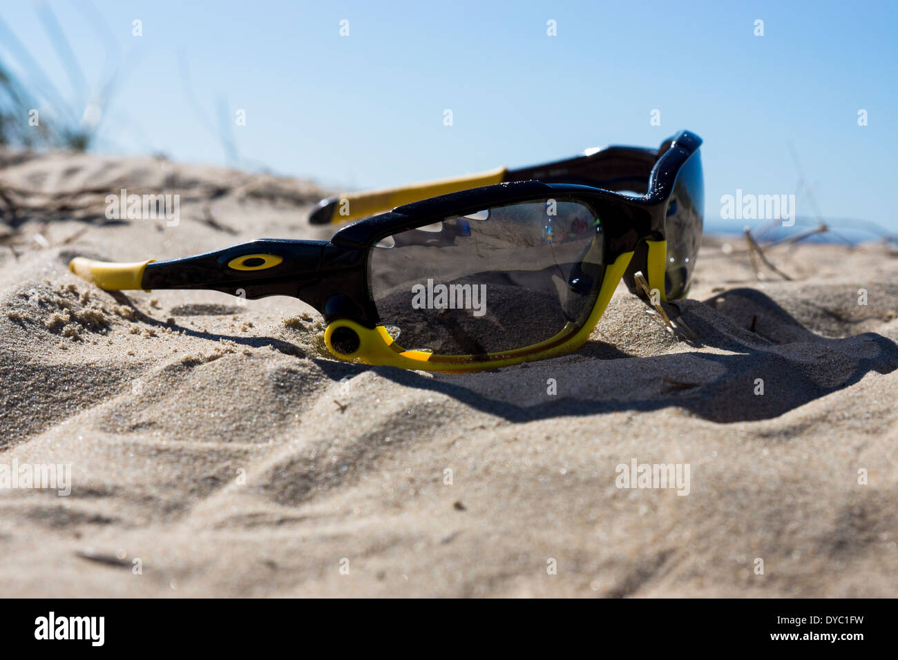 Branded Oakley Sunglasses left on tropical beach under th warm rich blue sky forgotten about on the ground Stock Photo