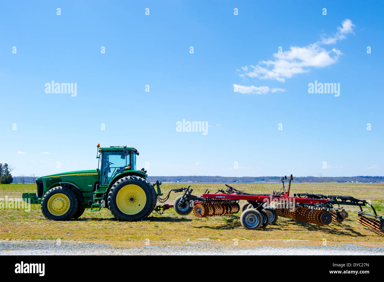 Tractor pulling plow with tillage disks in field Stock Photo