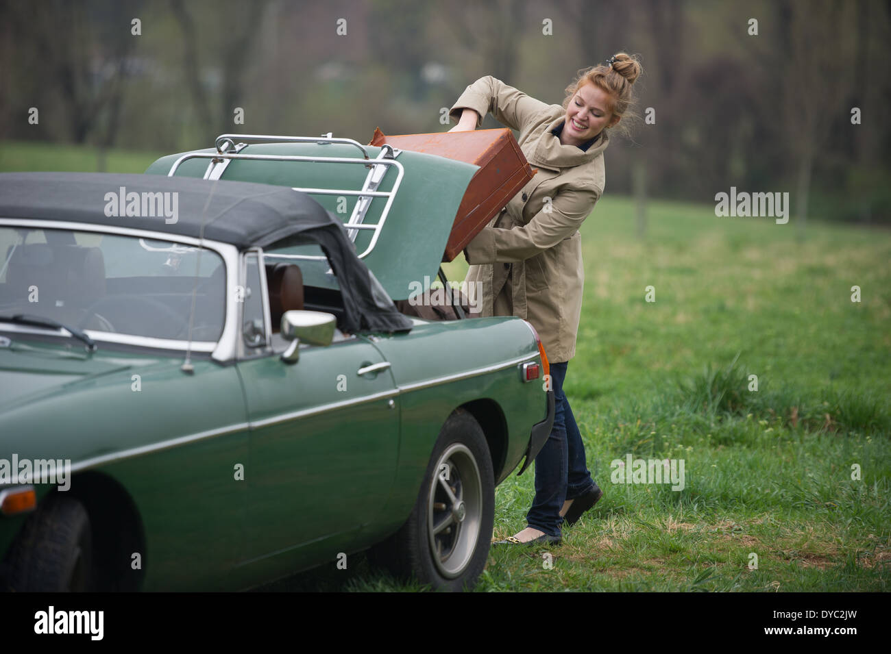 Woman with packed bags on journey next to classic british sports car Stock Photo