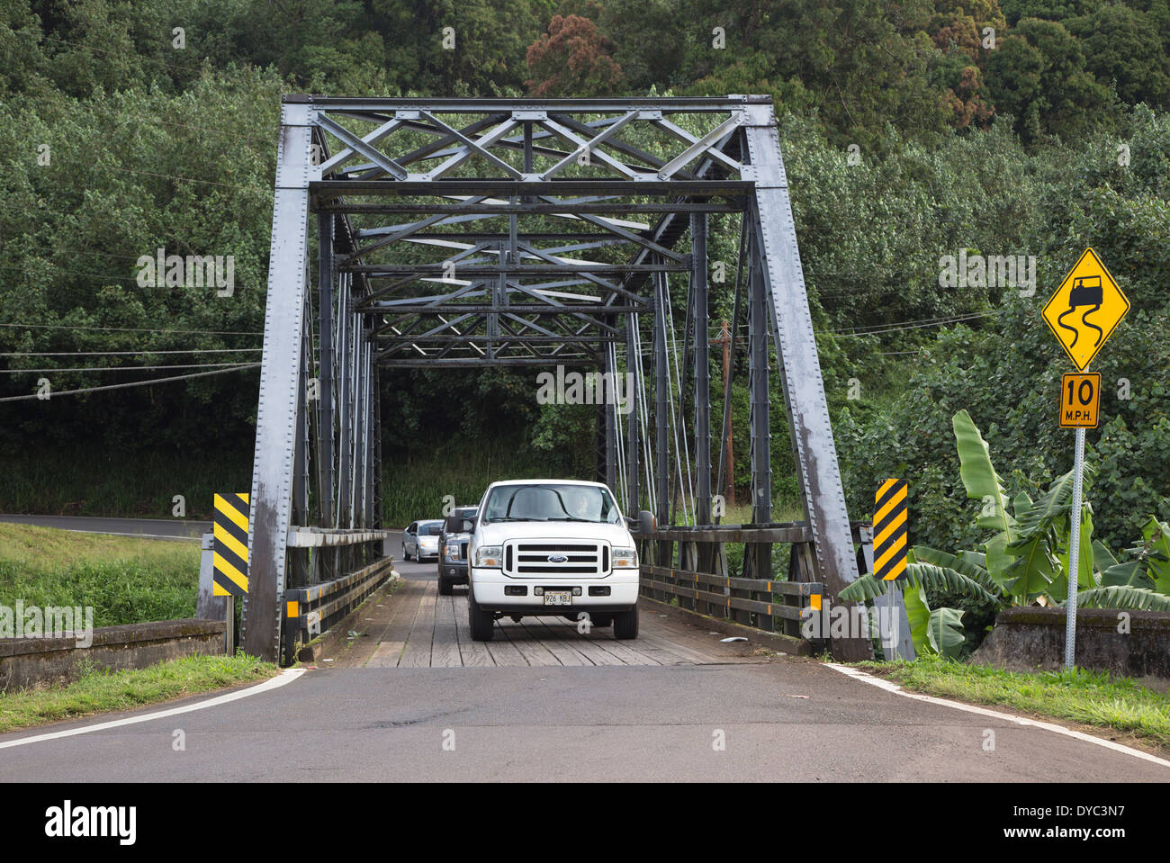 Vehicles driving across one lane bridge in the countryside Stock Photo