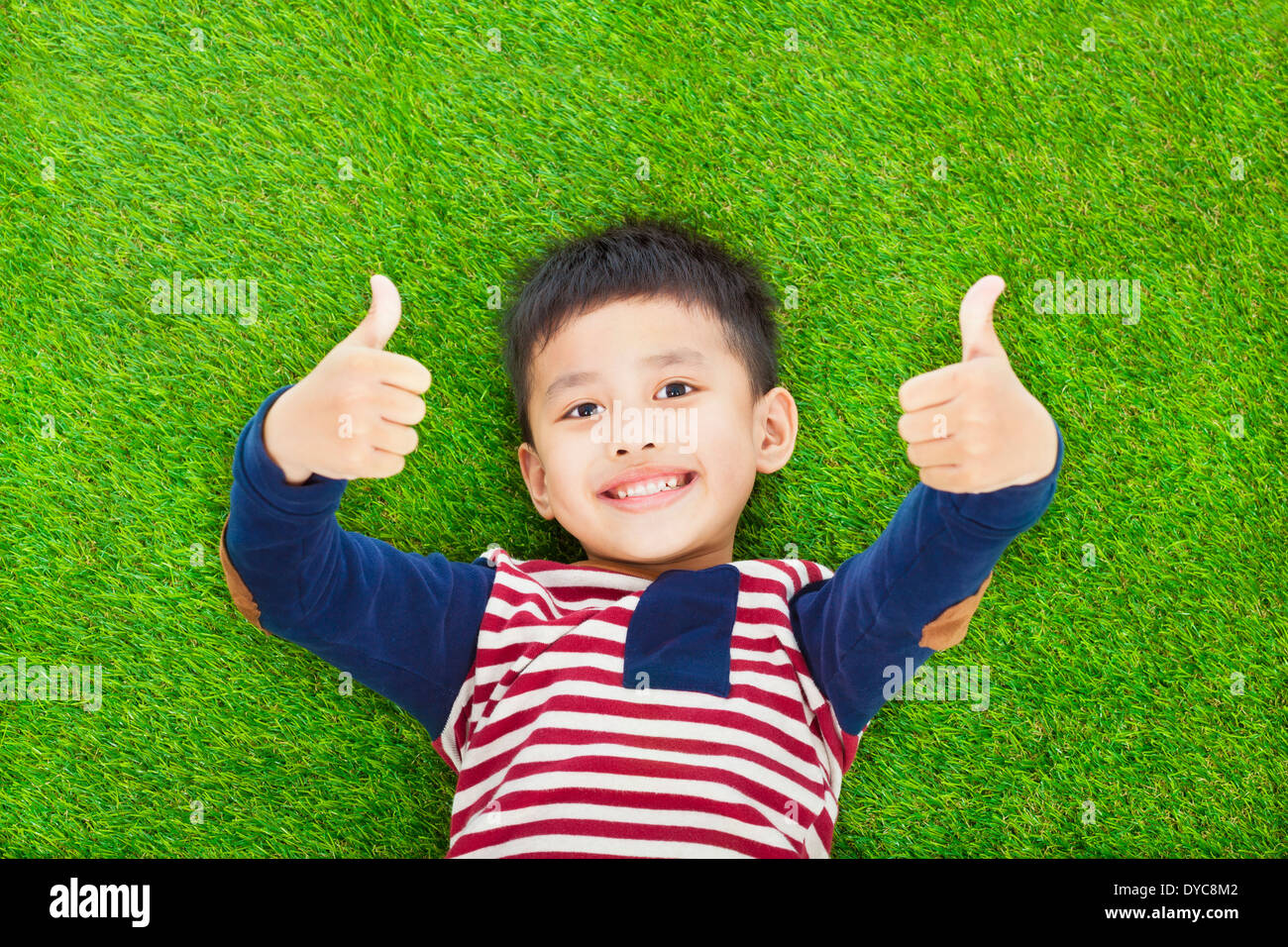 happy kid lying and thumb up on a meadow Stock Photo